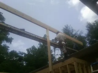Carpenter setting a ridge beam over a new addition frame — Ice Dam Removal by Roofing Brothers in Mc Dermott