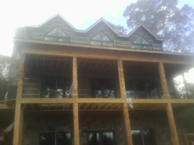 Dormers and porch framing on a large log home under construction — Roof Coating work by our crew in Mc Dermott
