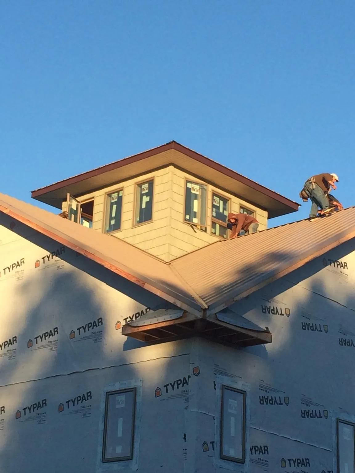 Roofers working around a rooftop cupola on a new metal roof at sunset — Roof Waterproofing in Mc Dermott by Roofing Brothers